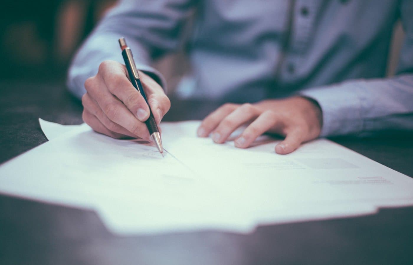 Hands completing official paperwork at a desk